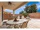 Covered back patio with outdoor dining set, grill, and fountain, ideal for entertaining and relaxation at 18131 W Addie Ln, Surprise, AZ 85374