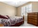 Cozy bedroom featuring a decorative wooden bed frame, matching wooden dresser, and bright natural light from the window at 18131 W Addie Ln, Surprise, AZ 85374