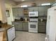 Well-lit kitchen featuring neutral-toned cabinets, granite countertops, and modern white appliances at 19139 N Alameda Dr, Surprise, AZ 85387
