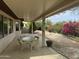 Relaxing covered patio with stone flooring, outdoor seating, and a lush backyard view at 19139 N Alameda Dr, Surprise, AZ 85387