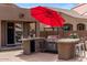This outdoor kitchen features granite countertops, stainless steel grill, and a red umbrella for shade at 21200 E Camacho Rd, Queen Creek, AZ 85142