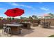 Outdoor kitchen space with bar seating, stainless grill, countertops, firepit, and shaded seating at 21200 E Camacho Rd, Queen Creek, AZ 85142