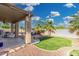 Relaxing backyard featuring a covered patio, lush green lawn, and palm trees for shade and privacy at 22351 N 67Th Dr, Glendale, AZ 85310