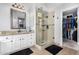 Bathroom featuring granite countertops, walk-in shower with glass door, and a spacious walk-in closet at 22351 N 67Th Dr, Glendale, AZ 85310