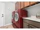 Laundry room featuring red washer and dryer, ample countertop space, and convenient overhead cabinets at 22351 N 67Th Dr, Glendale, AZ 85310