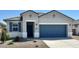 Charming single-story home with a blue two-car garage, neutral stucco and well-maintained landscaping at 22565 Rummler Ln, Maricopa, AZ 85138