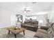 Spacious living room with a ceiling fan, wood-look tile flooring, and a view of the modern, white kitchen at 23523 N 117Th Dr, Sun City, AZ 85373