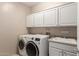 Clean laundry room with modern washer and dryer, sink, and ample cabinet storage space at 3733 E Kachina Dr, Phoenix, AZ 85044