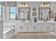 Elegant bathroom with a double sink vanity, decorative mirrors, and a separate soaking tub under a window at 3750 E Rochelle Cir, Mesa, AZ 85215