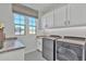 Well-lit laundry room equipped with modern appliances, ample storage, and stylish tile flooring at 3750 E Rochelle Cir, Mesa, AZ 85215