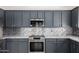 Modern kitchen features gray cabinets, stainless steel appliances, and granite countertops at 38662 N La Grange Ln, San Tan Valley, AZ 85140