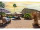 A large backyard with lounge chairs, umbrellas, a desert landscape and a covered patio at 43036 W Anne Ln, Maricopa, AZ 85138