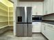 Modern kitchen with a stainless steel refrigerator, white cabinets and a walk in pantry next to the appliances at 4440 S Leisure Way, Gilbert, AZ 85297