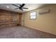 Spacious bedroom with wood accent wall, neutral carpet, window, and ceiling fan at 717 W Chilton St, Chandler, AZ 85225