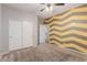 Stylish bedroom featuring chevron accent wall, ceiling fan and double closets at 7607 W Keim Dr, Glendale, AZ 85303
