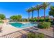 A sparkling community pool surrounded by palm trees and green landscaping, perfect for relaxation at 7769 W Bonitos Dr, Phoenix, AZ 85035
