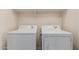 Close up of standard white washer and dryer with shelving above, located in the laundry room at 7769 W Bonitos Dr, Phoenix, AZ 85035