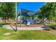 Community playground with blue slides and shade cover, set in a landscaped area with green grass and trees at 7769 W Bonitos Dr, Phoenix, AZ 85035