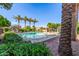 A community pool surrounded by lush landscaping and palm trees against a clear blue sky at 7769 W Bonitos Dr, Phoenix, AZ 85035