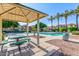 A shaded picnic area is located near the community pool, surrounded by lush landscaping and palm trees at 7769 W Bonitos Dr, Phoenix, AZ 85035