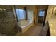 Bright bathroom with a tiled shower, soaking tub under a window, and neutral color palette at 8014 W Beaubien Dr, Peoria, AZ 85382
