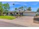 Inviting one-story home showcasing a lush green lawn, mature trees, and a spacious driveway leading to a two-car garage at 8582 E Via De Dorado --, Scottsdale, AZ 85258