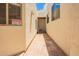 Exterior passageway featuring a security camera warning sign, narrow space, and neutral colored walls at 1018 E Knoll St, Mesa, AZ 85203