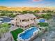 Expansive home with private pool, diving board, and tennis court nestled against a mountain backdrop at sunset at 14049 S 8Th St, Phoenix, AZ 85048