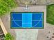 Aerial view of a blue sports court including a basketball hoop surrounded by gravel and green trees at 14049 S 8Th St, Phoenix, AZ 85048
