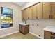 Spacious laundry room with modern sink, beautiful countertops, and custom-built wooden cabinetry at 14049 S 8Th St, Phoenix, AZ 85048