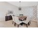 Dining area with a large wooden table, upholstered chairs, stylish light fixture, and patterned accent wall at 16409 N 65Th Pl, Scottsdale, AZ 85254