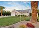 Well-maintained one-story home with a lush lawn, mature landscaping, and attached two-car garage at 16409 N 65Th Pl, Scottsdale, AZ 85254