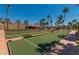 Well-maintained bocce ball courts amidst a lush green space surrounded by landscaping and palm trees at 18522 N Mica Dr, Sun City West, AZ 85375