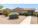 A cozy tan house with a manicured yard, decorative bushes, and a gravel landscape offers low maintenance curb appeal at 18522 N Mica Dr, Sun City West, AZ 85375