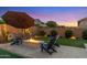 Relaxing backyard with a stone fire pit, Adirondack chairs, and ambient lighting for cozy evenings at 21283 E Camacho Rd, Queen Creek, AZ 85142