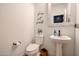 Stylish powder room with pedestal sink, toilet, decorative mirror, and wall art at 2158 N 212Th Ave, Buckeye, AZ 85396
