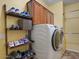 Bright laundry room features a modern washer and dryer, wooden shelving, and cabinet storage at 21720 E Domingo Rd, Queen Creek, AZ 85142
