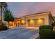 Home at dusk featuring a well-manicured front yard, lit garage, and charming desert landscape at 23213 N Del Monte Dr, Sun City West, AZ 85375