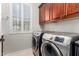 Laundry room with wooden cabinets, front load washer and dryer, and shuttered window at 23213 N Del Monte Dr, Sun City West, AZ 85375