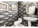 This charming powder room features designer wallpaper, framed artwork, and a decorative mirror over a pedestal sink at 23213 N Del Monte Dr, Sun City West, AZ 85375
