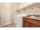 Convenient laundry room featuring a washer, dryer, built-in shelving and a utility sink at 25667 W Primrose Ln, Buckeye, AZ 85326