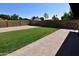 Large backyard featuring green grass, gravel area, brick-paved patio, and a secure brick wall at 3310 W Sweetwater Ave, Phoenix, AZ 85029