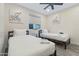 Bright bedroom with two twin beds, modern ceiling fan, and stylish decor at 3615 E Charter Oak Rd, Phoenix, AZ 85032