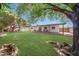 Well-maintained backyard with green grass, a covered patio, storage shed, and mature landscaping at 4808 W Shaw Butte Dr, Glendale, AZ 85304