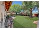 Scenic backyard with green grass, a covered patio, and established trees, creating a private retreat at 4808 W Shaw Butte Dr, Glendale, AZ 85304