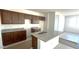 An unfinished kitchen features dark brown cabinets, granite countertops, and a center island with a sink at 5633 S 253Rd Ave, Buckeye, AZ 85326
