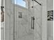 Close up of a glass enclosed marble shower with a mosaic tile floor and black hardware at 5756 E Star Valley St, Mesa, AZ 85215