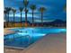 Community pool illuminated at twilight, with mountain views, providing a serene setting for relaxation at 5756 E Star Valley St, Mesa, AZ 85215