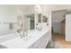 Bright bathroom featuring double sinks, a large mirror, and access to a walk-in closet at 6122 E Saddleback St, Mesa, AZ 85215
