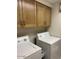 Bright laundry area features cabinetry above a modern washer and dryer set for efficient home convenience at 6122 E Saddleback St, Mesa, AZ 85215